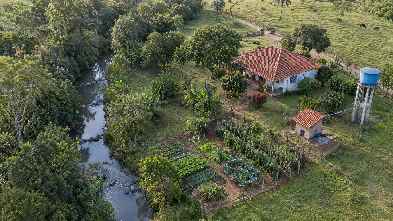 Vista aérea de propriedade rural com rio, horta, caixa d'água e casa de bomba do poço